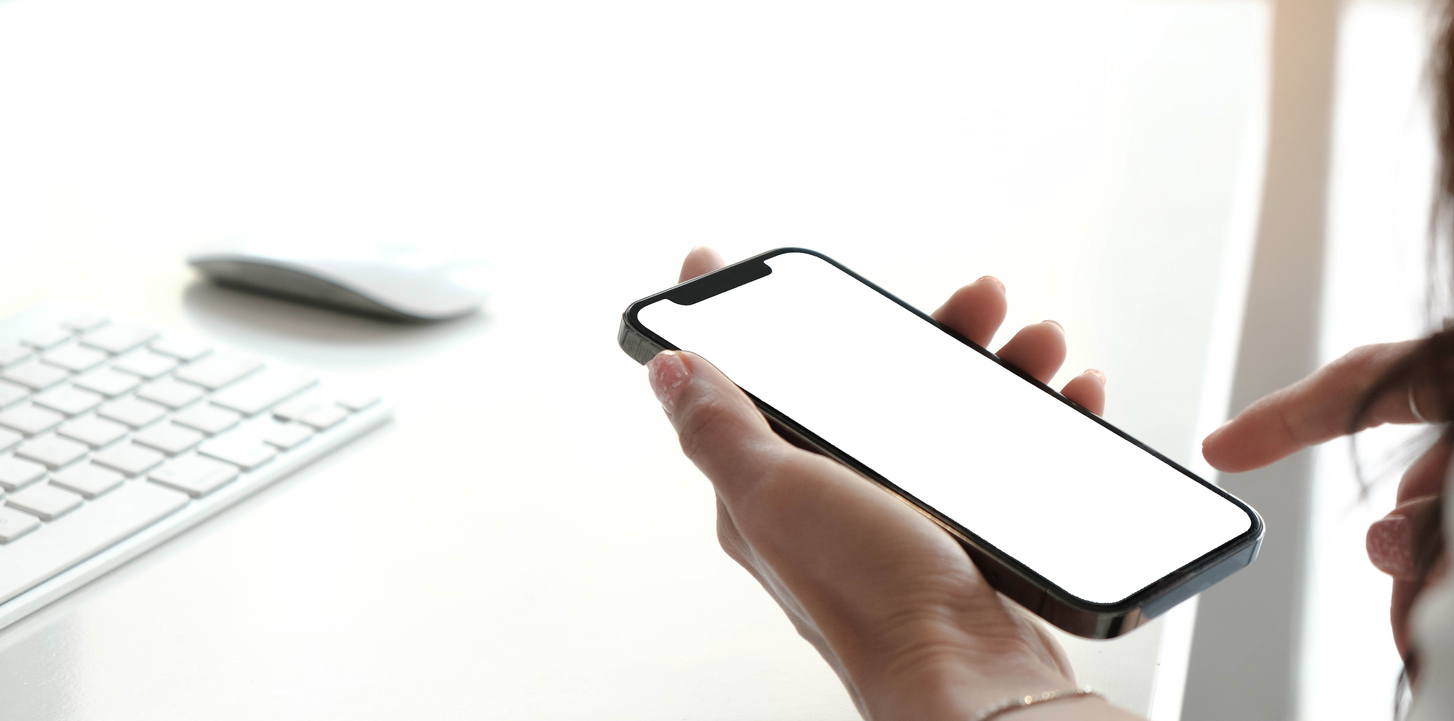 Mockup image blank white screen cell phone.women hand holding texting using mobile on desk at home office.